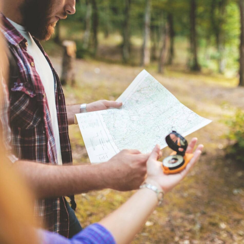 people outdoors viewing a map and compass